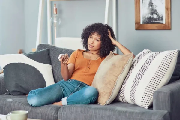 Girl using TV romote and sitting on sofa